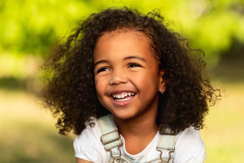 beautiful little girl with curly hair laughing outdoor