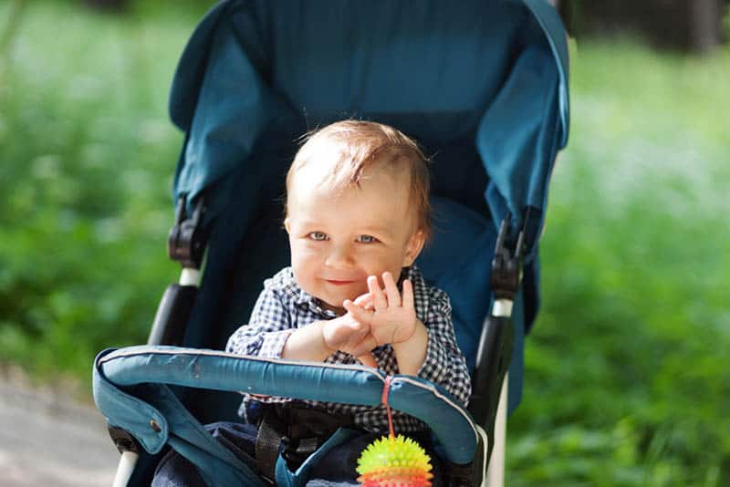 cute baby boy sitting in a stroller in the park