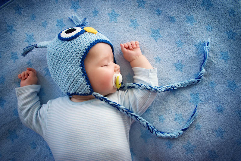 cute baby boy with winter hat sleeping on the blue blanket