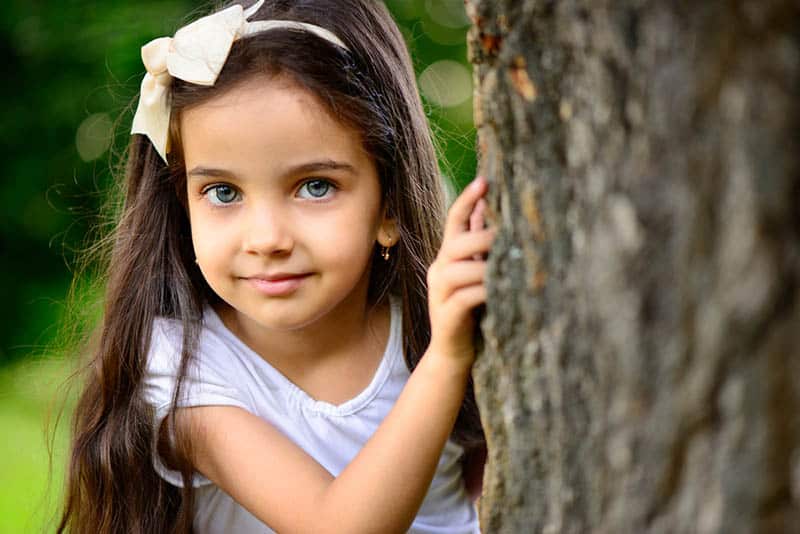 hispanic girl with deep blue eyes in sunny park
