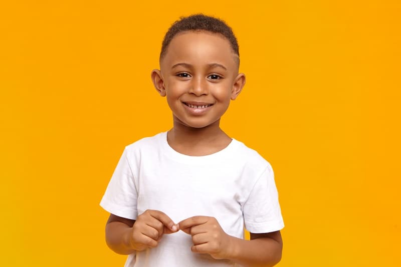little boy smiling while posing in front of a yellow background