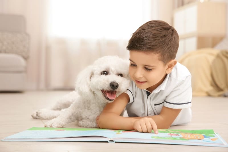 little boy reading on the floor with his cute puppy
