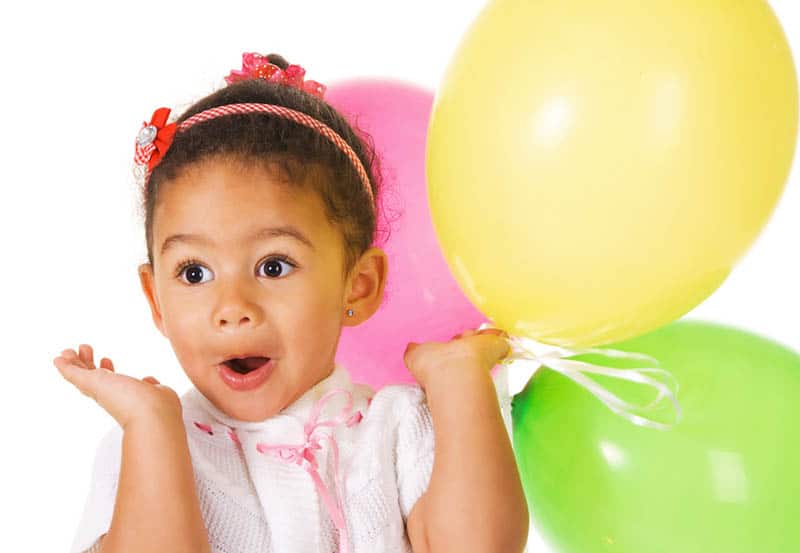 surprised little girl holding colorful balloons