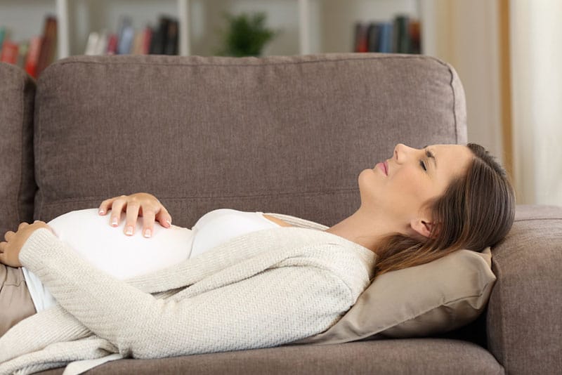 young pregnant woman feeling pain beacuse of baby kicks in the belly