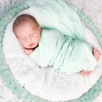 newborn baby sleeping while swaddled in a soft blanket