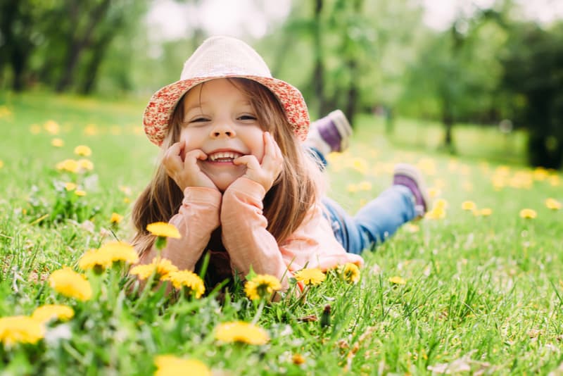 Cute little girl with hat lying on the grass