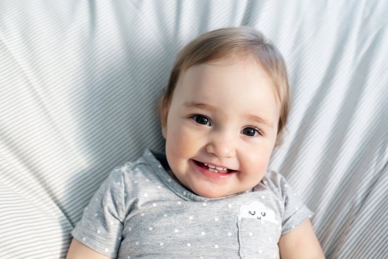 Cute smiling baby girl laying in the bed