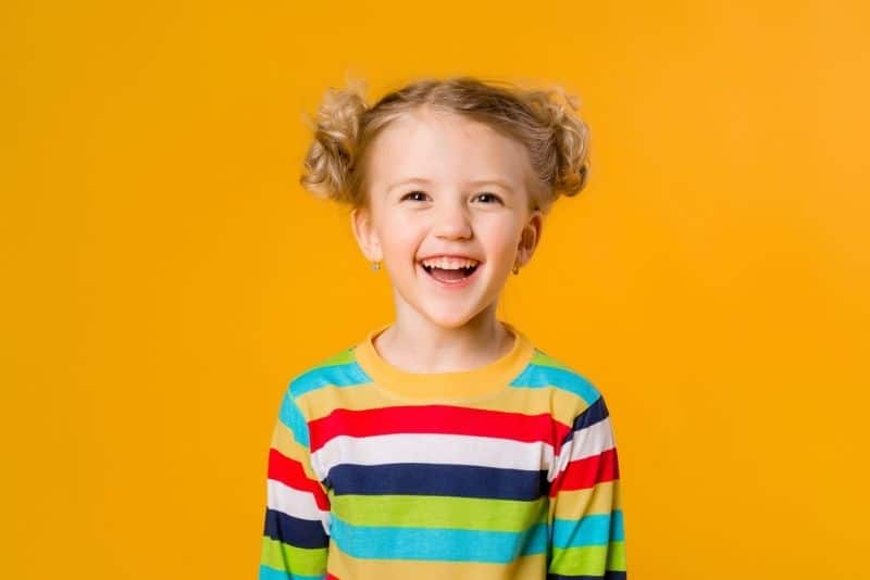blonde little girl in a colorful shirt smiling