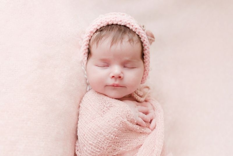 Newborn baby girl sleeping in pink swaddle