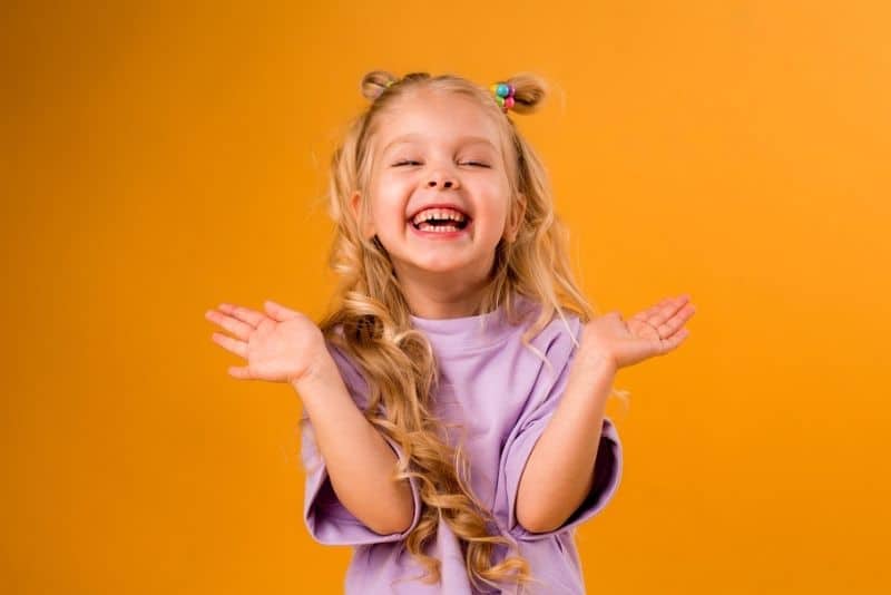 little blond girl in a purple t-shirt laughing