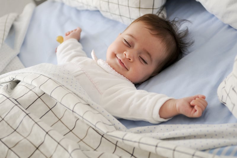 Smiling baby girl lying on a bed sleeping 