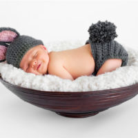 baby sleeping with his butt in the air in a small basket