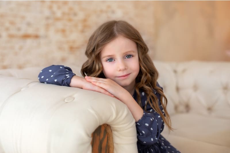 little girl sitting on a couch in living room