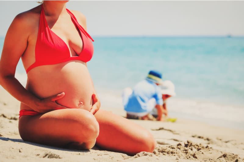 pregnant mother relax on beach while kids play with sand