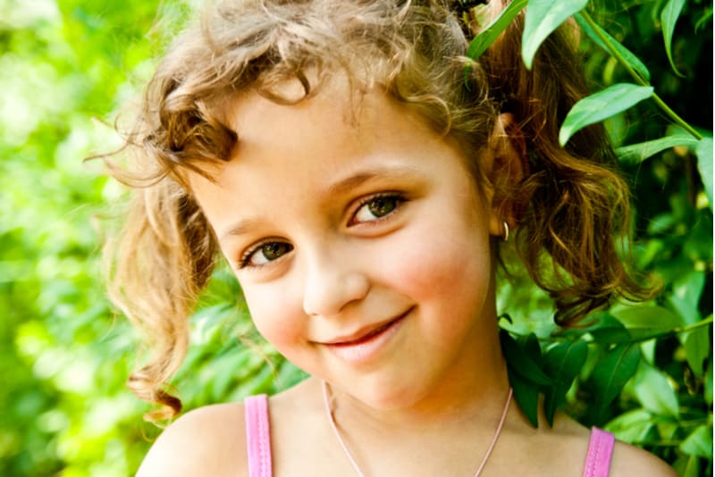 smiling little girl with curly hair outdoors