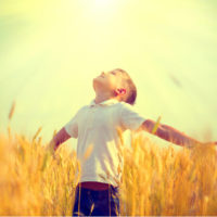 little boy spreading his arms wide open towards the sky on a sunny day