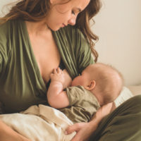young woman breastfeeding her baby in bed