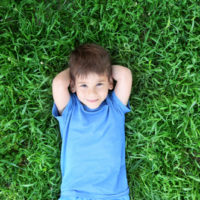 cute little smiling boy lying on the grass