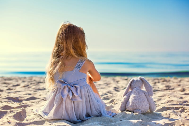 Cute little girl sitting at ocean beach