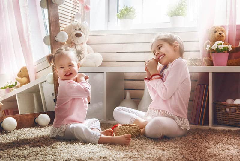 Funny lovely sisters are having fun in kids room