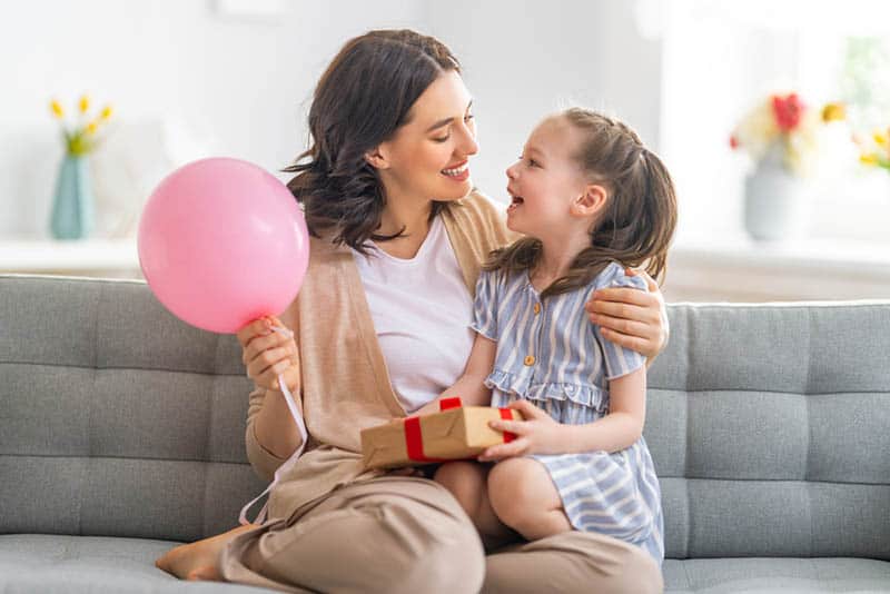 Mum and daughter smiling and holding baloon
