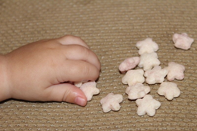 the hand of a baby reaching for puffs