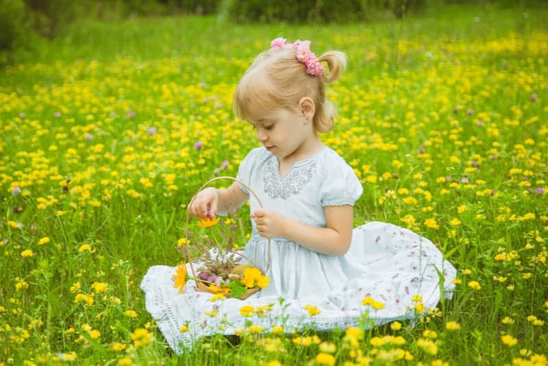 blonde little girl playing with the flowers