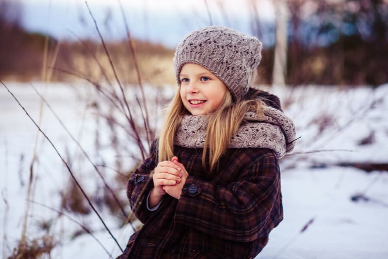 cute little girl in a plaid coat and a cozy hat 