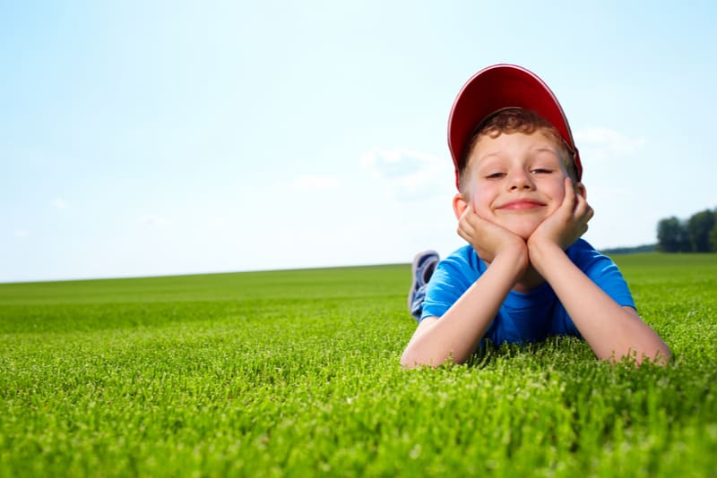 happy little boy laying on the grass