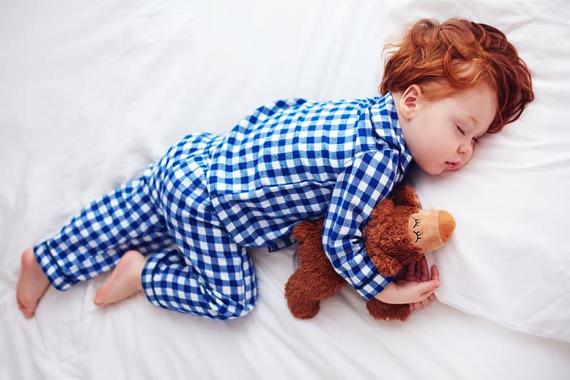 little boy wearing cotton pijama sleeping with toy