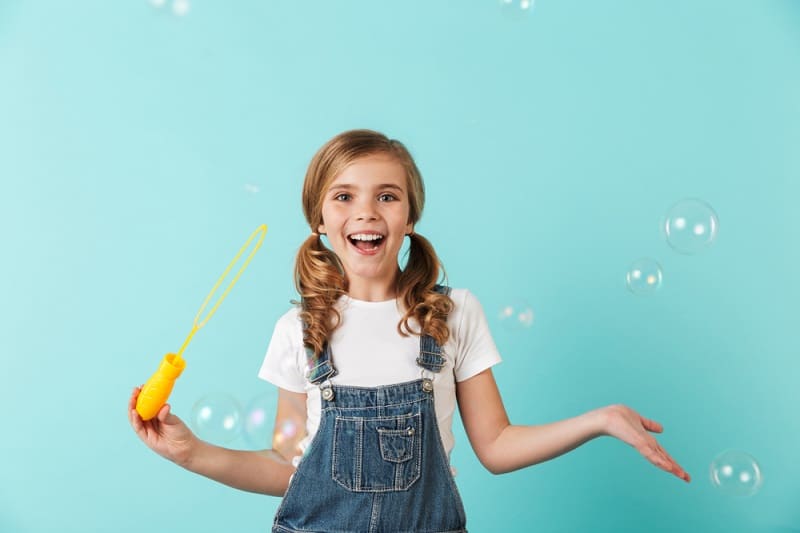 little girl with pigtails blowing bubbles and laughing