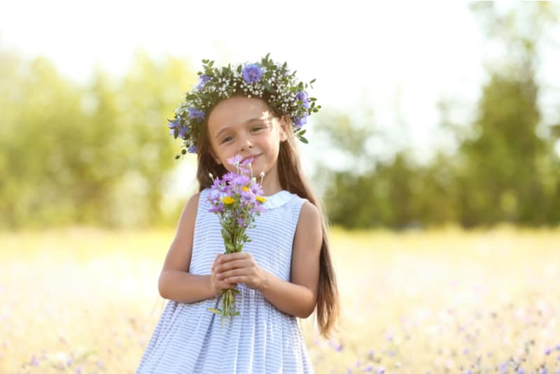 little girl holding beautiful wreath with bouquet of wildflowers