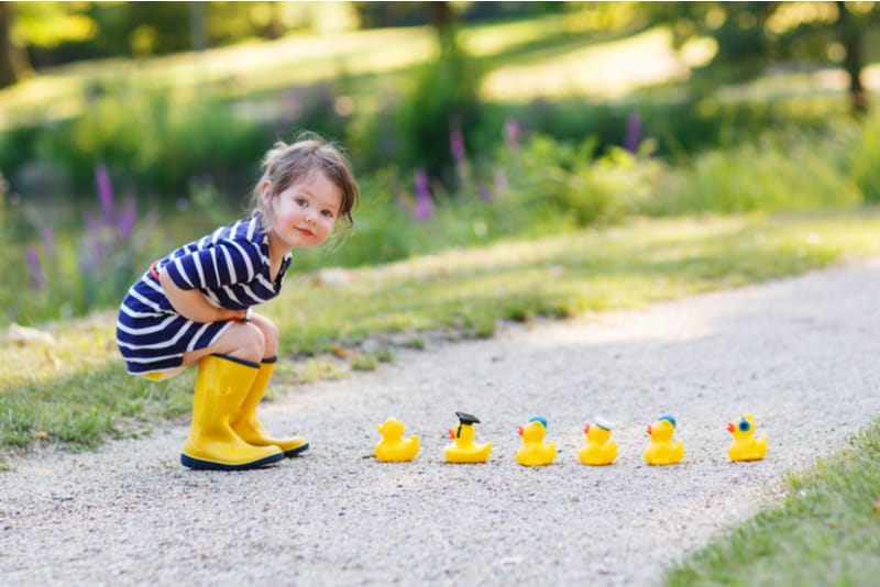 little girl playing with yellow rubber ducks 