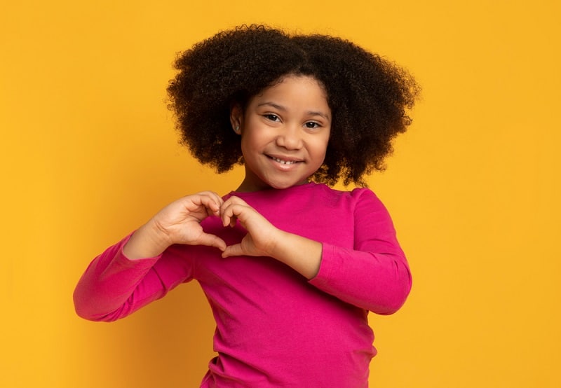 little girl making a heart shape with her hands