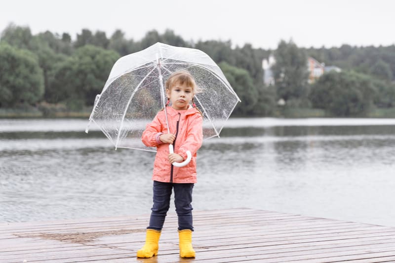 sad little girl in yellow rainboots with umbrella