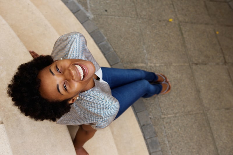smiling young african woman sitting on steps