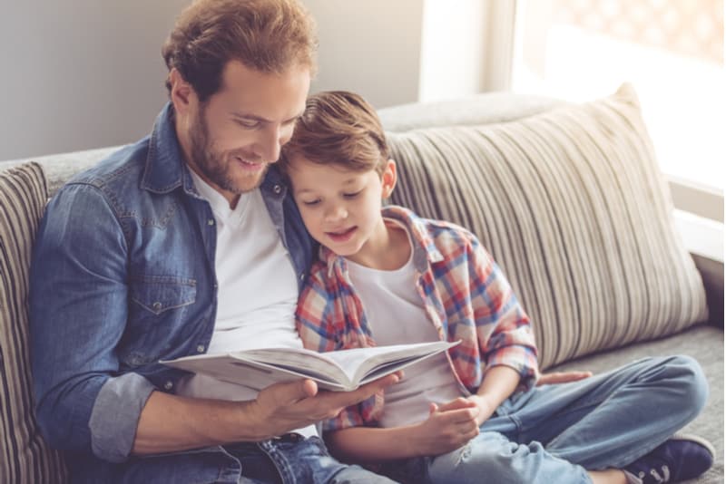 uncle and little boy are reading a book and smiling