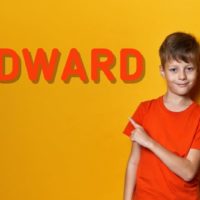 cute young boy with orange t-shirt pointing to the name Edward