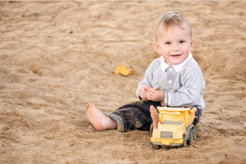 Boy sitting in sandpit and smiling
