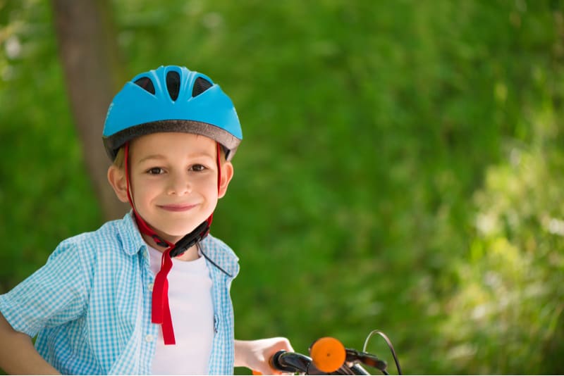 Cute little boy wearing helmet in forest