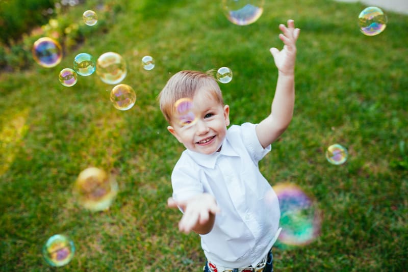Little boy with soap bubbles in summer park