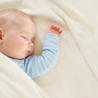 little boy sleeping on soft white blanket