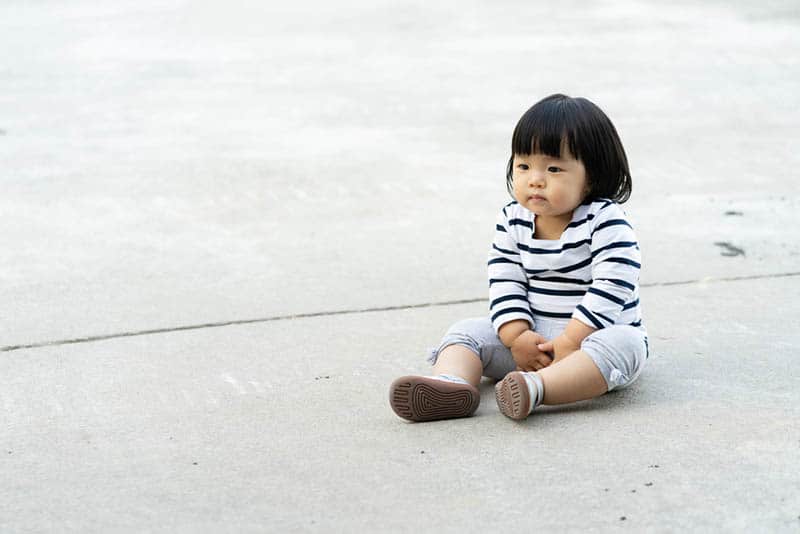 adorable little girl needs to pee while sitting outdoor