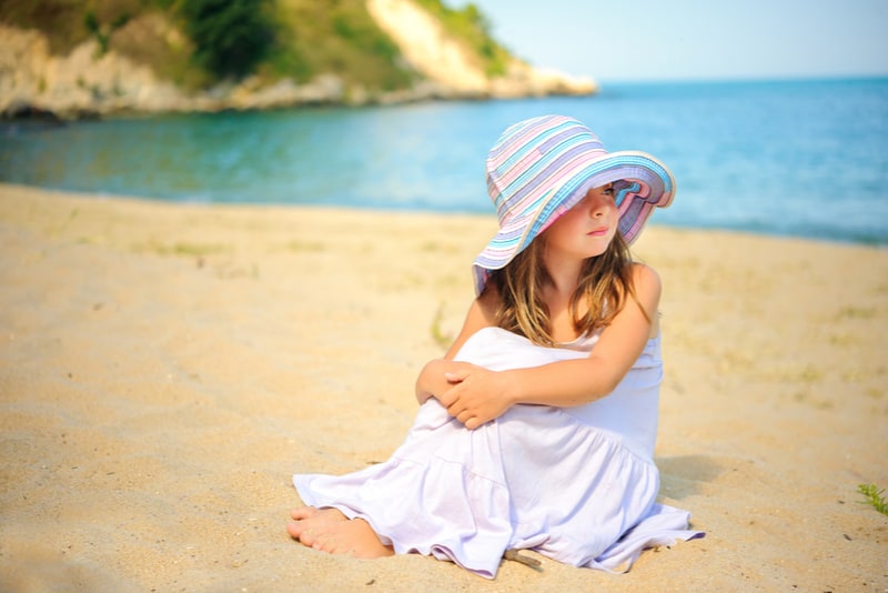 beautiful little girl sits on the beach