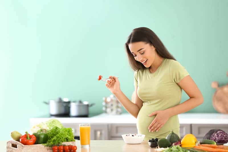 beautiful pregnant woman eating healthy food in the kitchen