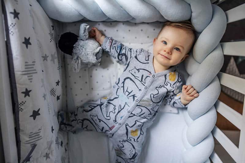 cute baby boy in pijama lying in crib on his back