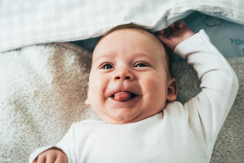 cute baby boy smiling while sticking tongue out