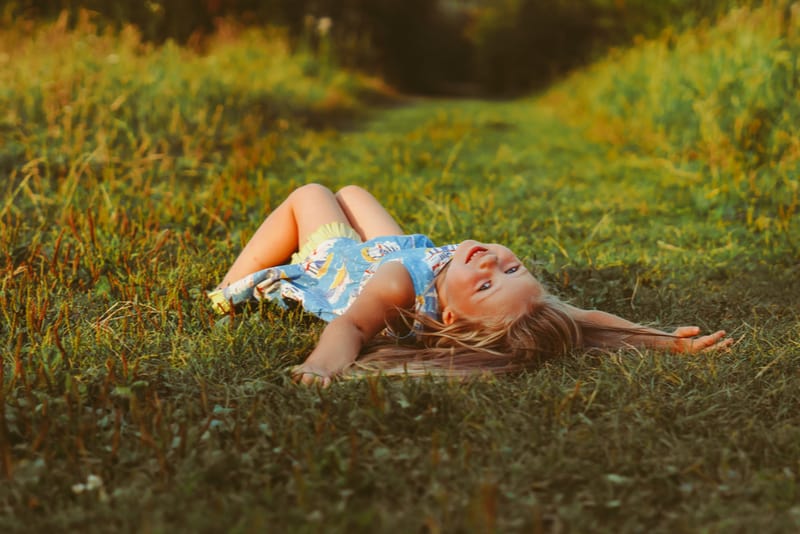 cute little girl lying on the green grass