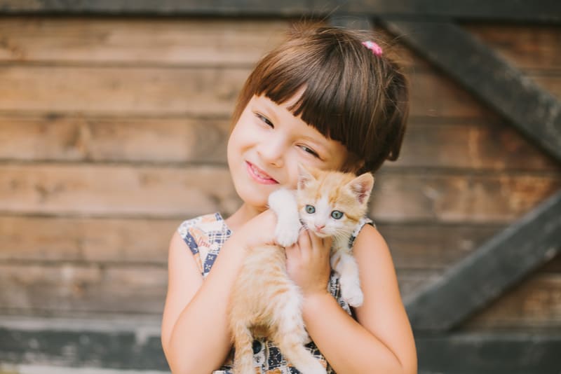 happy little girl holding a cat in her arms