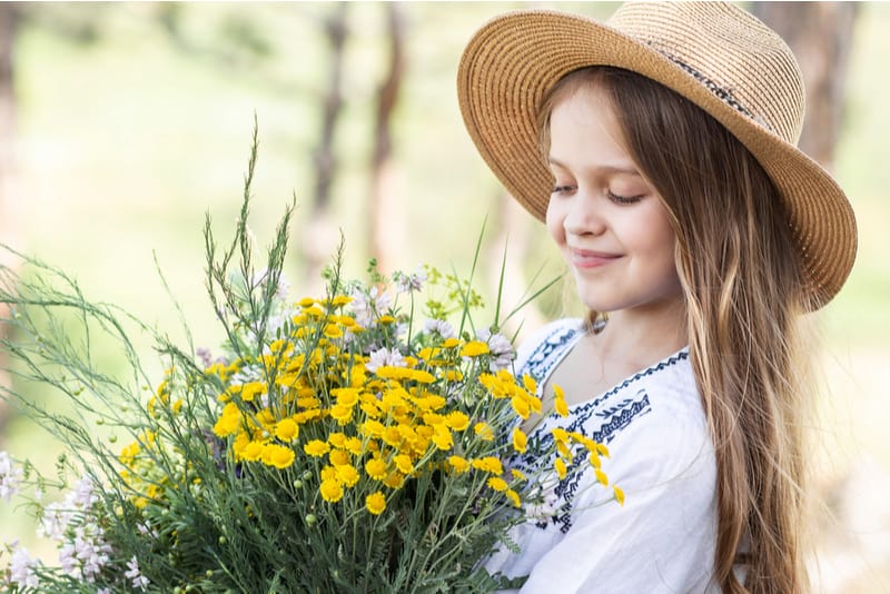 little girl wearing hat holding flowers in her hands